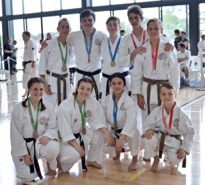 a group of young students wearing different coloured belts are showing there medals