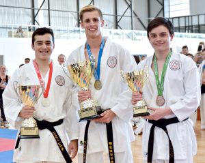 three karate students holding the trophies they have just won