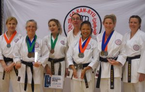four women black belt competitors wearing medals