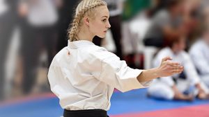 a young blonde woman performs a karate stance
