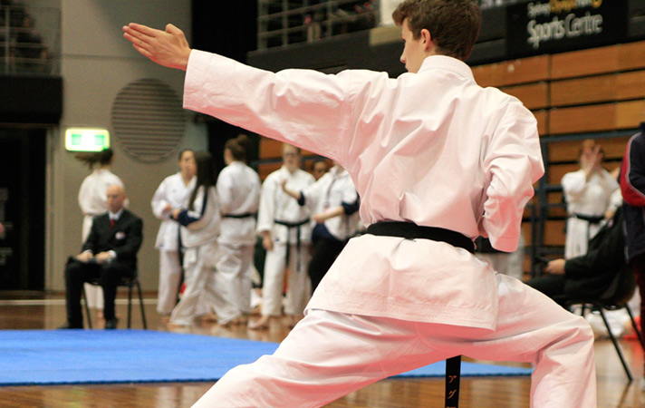 a young boy wearing a black belt performs a karate move at a gkr karate world cup