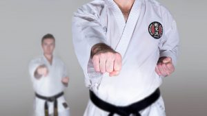 two gkr karate students with black belts perform a karate power stance