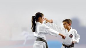 two gkr karate students wearing black belts, performing blocks