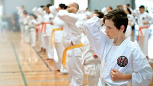 a row of kids wearing yellow belts perform a karate stance