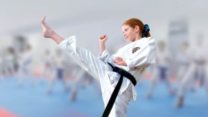 young girl in a gkr karate gi performs a stance wearing a black belt