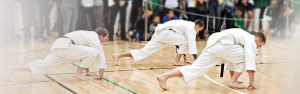 three karate students perform a stance, all three of them are black belt