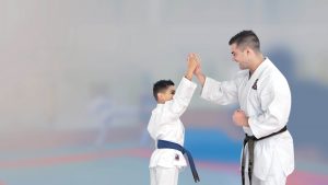 a little boy wearing a gi defends himself from a young man performing a karate move