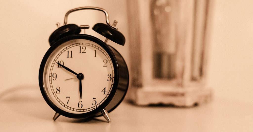 procrastination a problem. alarm clock on bedside table