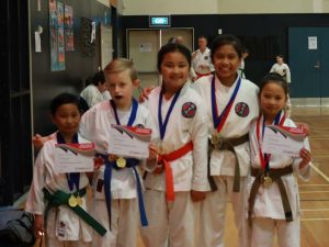 a group of children celebrating with medals from karate