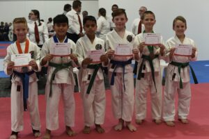 a group of small children wearing medals, they are holding up certificate of participations