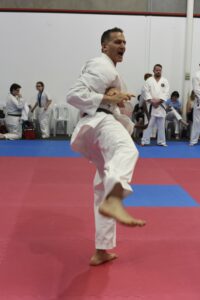 a man wearing a black belt performs a karate move