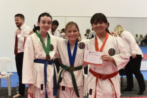 three young karate students celebrating their medals