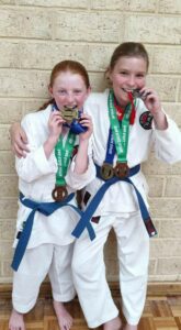 two students wearing blue belts have medals