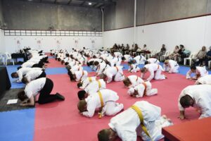 a large group of men and women wearing gis performing a bow at a karate dojo