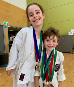 two small children showing off there large amount of medals