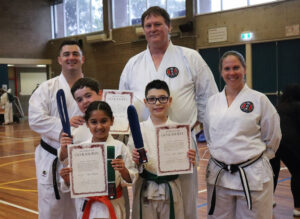a family of 6 celebrate with certificates of rank and with new belts