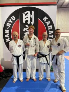 two young men and two old men wearing a gi standing together holding certificates of competition at a gkr karate dojo