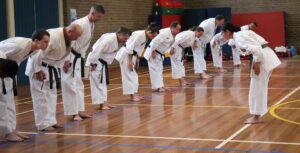 a row of men wearing black belts, bowing