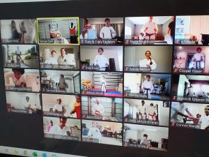 a photo taken of a computer screen showing multiple people in a zoom meeting wearing gi for karate grading
