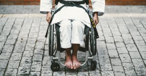 Woman in a wheelchair wearing a karate gi and black belt