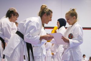 a sensei gives a certificate to a younger gkr karate student
