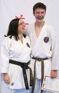A mother and son wearing karate gis. The mother is looking proudly up at her son.