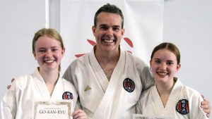 A father and his two daughters dressed in gis after a karate grading