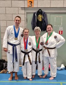 four people stand next to each other, wearing medals they earnt from the northern uk regional titles.