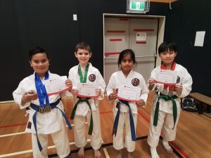 four young karate students showing there certificate of participation