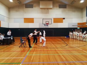 a small boy performs bows in front of a sensei, with onlookers watching