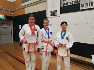 three karate students with there certificates and medals