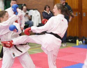 two students performing a karate kick and the other trying to block