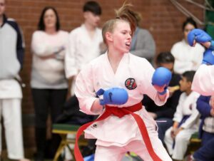 a young boy wearing a gkr karate gi and a red belt performs a karate move