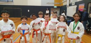 a small group of karate students holding certificate of participations